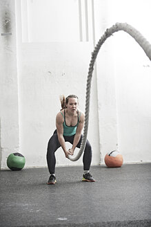 Frau trainiert mit einem Kampfseil in einem Cross-Training-Fitnessstudio - ISF04076