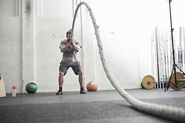 Ein Mann trainiert mit einem Kampfseil in einem Cross-Training-Fitnessstudio - ISF04079