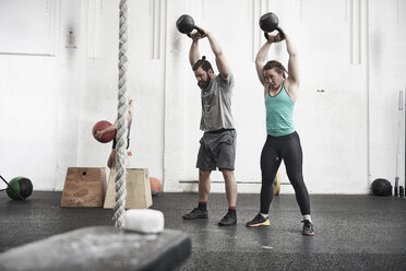 Couple working out with kettlebells in cross training gym - ISF04084