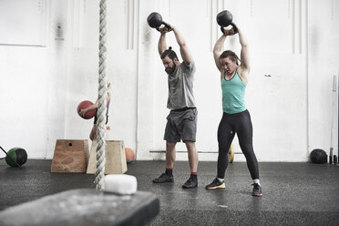 Paar trainiert mit Kettlebells im Cross-Training-Fitnessstudio - ISF04084