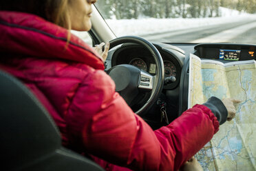 Woman driving car, pointing at map, mid section - ISF04170