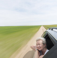 Senior woman leaning on car window enjoying wind in face - ISF04218