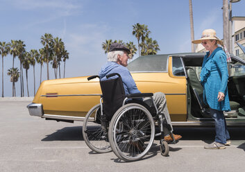 Ältere Frau unterhält sich mit ihrem Mann im Rollstuhl in einem Oldtimer am Venice Beach, Kalifornien, USA - ISF04242