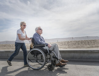 Ältere Frau schiebt ihren Mann im Rollstuhl am Strand, Santa Monica, Kalifornien, USA - ISF04243
