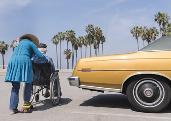 Ältere Frau schiebt ihren Mann im Rollstuhl in einem Oldtimer am Venice Beach, Kalifornien, USA - ISF04245