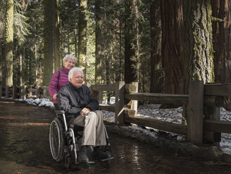 Ältere Frau schiebt ihren Mann im Rollstuhl durch den Wald im Sequoia National Park, Kalifornien, USA - ISF04246