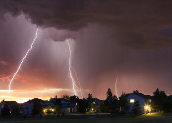Forked lightning in orange sky over urban area, Aurora, Colorado, United States, North America - ISF04265