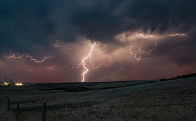 Forked lightning in orange sky over rural area, Grant, Nebraska, United States, North America - ISF04270