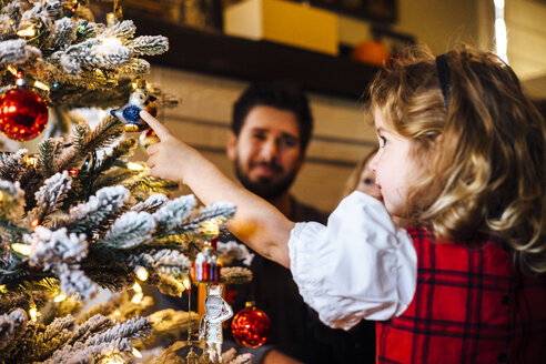 Weibliches Kleinkind mit Eltern, die auf eine Christbaumkugel zeigen - ISF04300