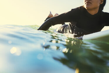 Young female surfer paddling surfboard at sea, Newport Beach, California, USA - ISF04318