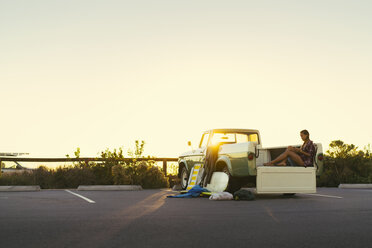 Junge Surferin schaut auf ihr Smartphone auf dem Rücksitz eines Pickups in Newport Beach, Kalifornien, USA - ISF04327