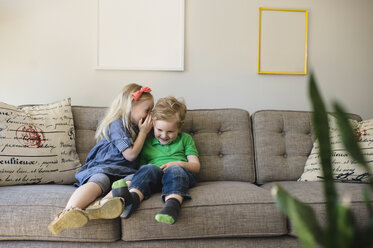 Mädchen auf dem Sofa flüstert mit ihrem Bruder - ISF04352