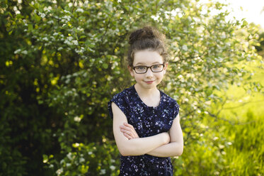 Portrait of girl wearing eye glasses in field with blossoming trees - ISF04386