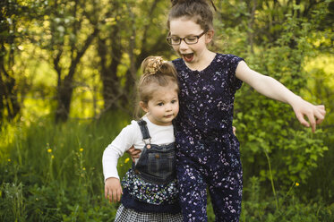 Mädchen und kleine Schwester spielen auf einem Feld mit Bäumen - ISF04387