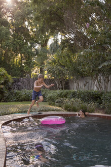 Kinder schwimmen im Gartenpool, ein kleiner Junge springt hinein, mitten in der Luft - ISF04401