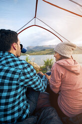 Paar sitzt im Zelt, trinkt heiße Getränke und schaut auf die Aussicht, Heeney, Colorado, Vereinigte Staaten - ISF04412