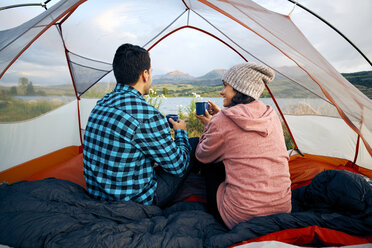 Paar sitzt im Zelt, trinkt heiße Getränke und betrachtet die Aussicht - ISF04414
