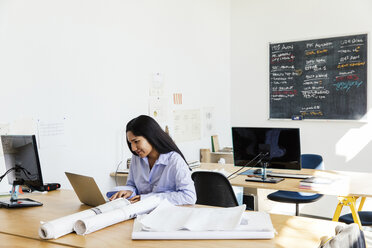 Frau sitzt am Schreibtisch im Büro und arbeitet am Laptop - ISF04451