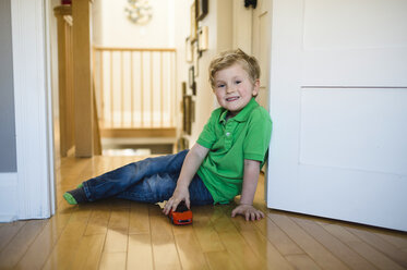 Porträt eines Jungen mit Spielzeugauto auf dem Boden sitzend - ISF04463
