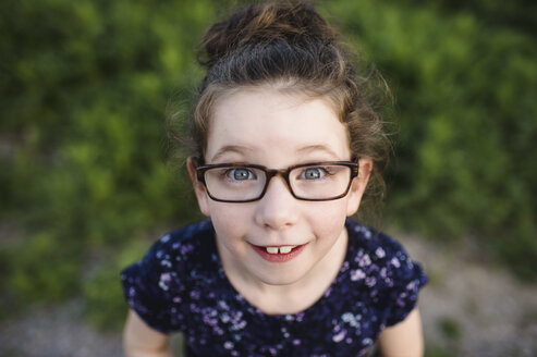 Portrait of cute girl wearing eye glasses looking up at camera - ISF04473