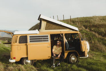 Young male skateboarder looking out from vintage recreational vehicle, Exeter, California, USA - ISF04491