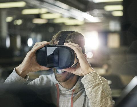 Mann arbeitet mit VR-Brille und Laptop, lizenzfreies Stockfoto