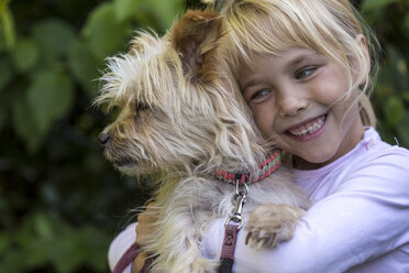 Porträt eines glücklichen kleinen Mädchens, das seinen Hund knuddelt - JFEF00866