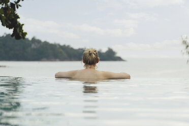 Thailand, Phuket, back view of woman relaxing in infinity pool - CHPF00466