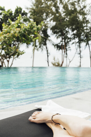 Thailand, Beine einer Frau beim Entspannen am Pool, lizenzfreies Stockfoto