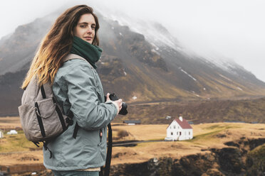 Island, Porträt eines Wanderers mit Rucksack und Kamera - KKAF00996