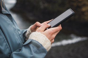 Island, Hände einer Frau mit Smartphone - KKAF01012