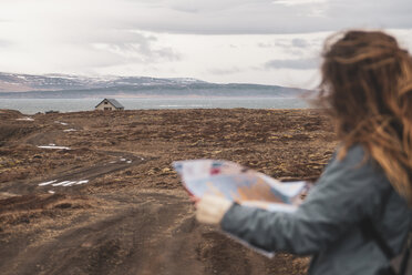 Island, Frau mit Landkarte in Landschaft mit einzelnem Haus - KKAF01027