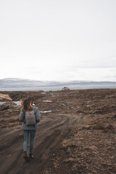 Island, Rückenansicht einer Frau mit Rucksack beim Wandern in der Landschaft - KKAF01029