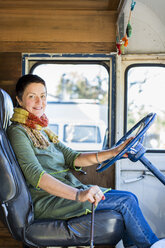 Porträt einer reifen Hippie-Frau auf dem Fahrersitz eines Wohnmobils - ISF04513