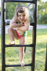 Porträt eines Mädchens im Badeanzug auf einem Klettergerüst im Garten - ISF04526
