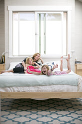 Portrait of girl fooling around on bed with mother and sister - ISF04533