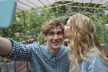 Couple in garden kissing, taking selfie - ISF04563