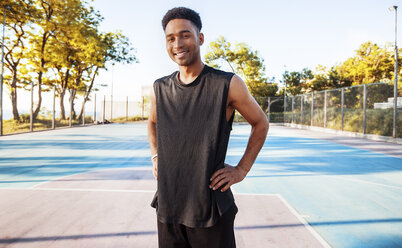 Porträt eines jungen Mannes auf dem Basketballplatz, lächelnd - ISF04575