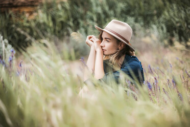 Mid adult woman sitting in long grass, thoughtful expressions - ISF04578