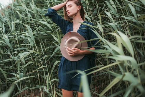 Mid adult woman beside long grass, touching hair, breathing in fresh air - ISF04579