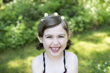 Portrait of young girl outdoors, wearing daisies in hair, smiling - ISF04587
