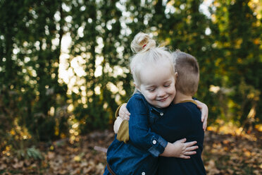 Cute female toddler hugging twin brother in autumn garden - ISF04588