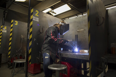 Metallschmiedin beim Schweißen von Metall an der Werkbank - ISF04607