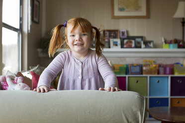 Porträt eines jungen Mädchens mit roten Haaren, das sich an ein Sofa lehnt - ISF04632