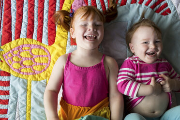 Portrait of two young sisters lying on blanket, laughing - ISF04635