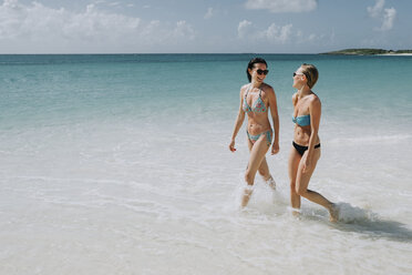 Two mid adult sisters strolling in blue sea, Anguilla, Saint Martin, Caribbean - ISF04725