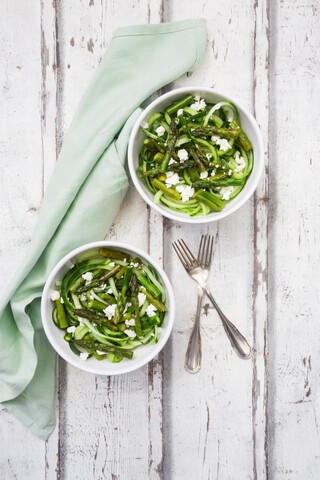 Grüner Spargelsalat mit spiralförmig gewundenen Gurken und Feta-Käse, lizenzfreies Stockfoto