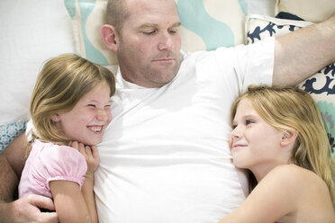 Overhead view of mature man between two daughters on bed - ISF04756