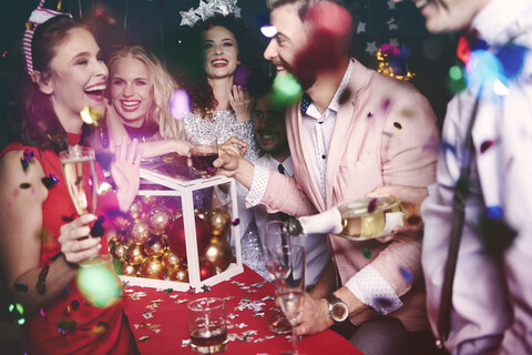 Gruppe von Freunden auf einer Party, die herumalbern und Getränke einschenken, lizenzfreies Stockfoto