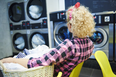 Frau beobachtet Waschmaschinen in einem Waschsalon - ISF04779